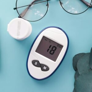A top view of a glucometer, test strip, and glasses on a blue background, symbolizing health management.